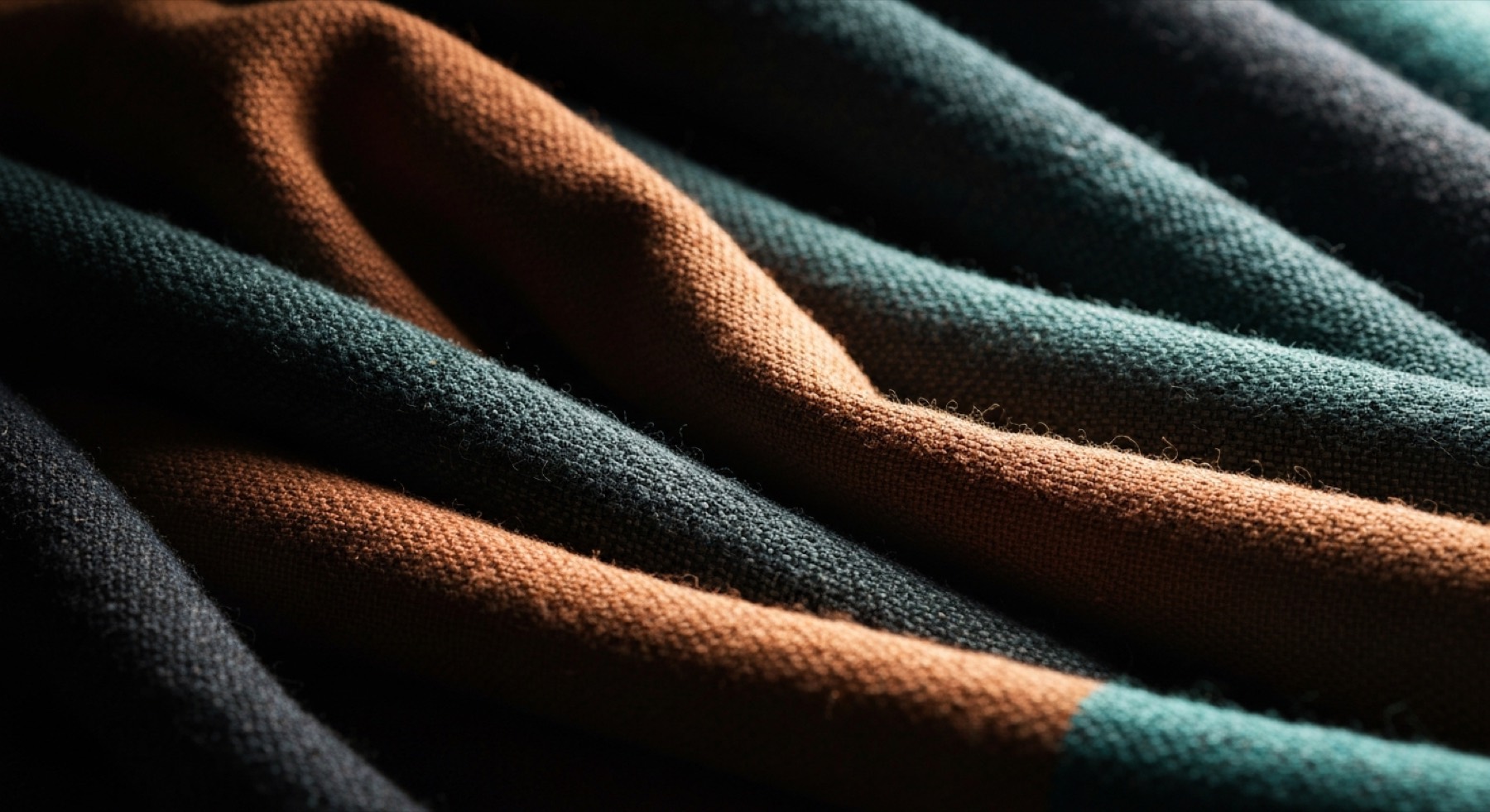 Heavy handwoven cloth in deep folds, terracotta and dark teal running through it.