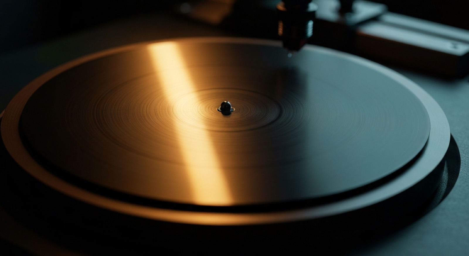 A blank lacquer disc on a cutting lathe, its surface smooth and uncut, one warm light raking across it.
